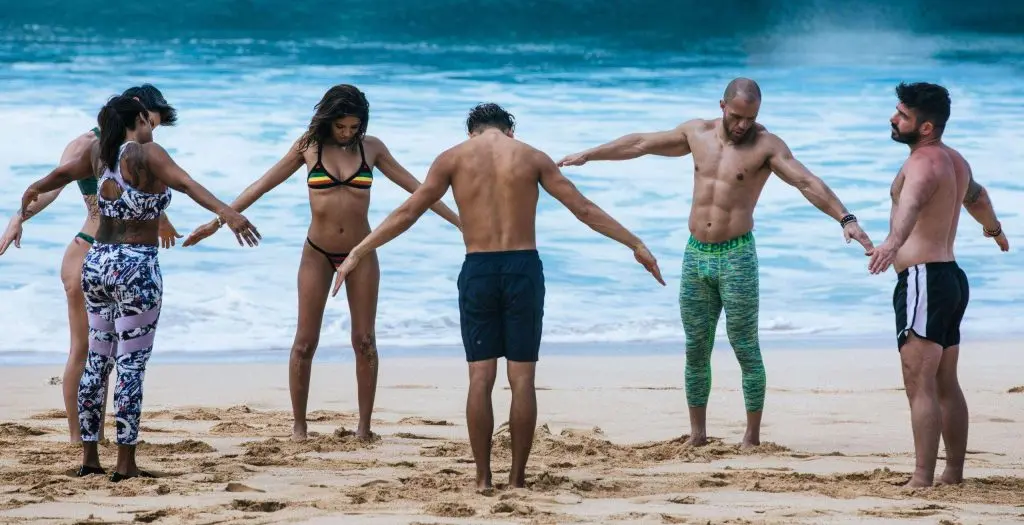 Group stretching on the sand in front of the ocean