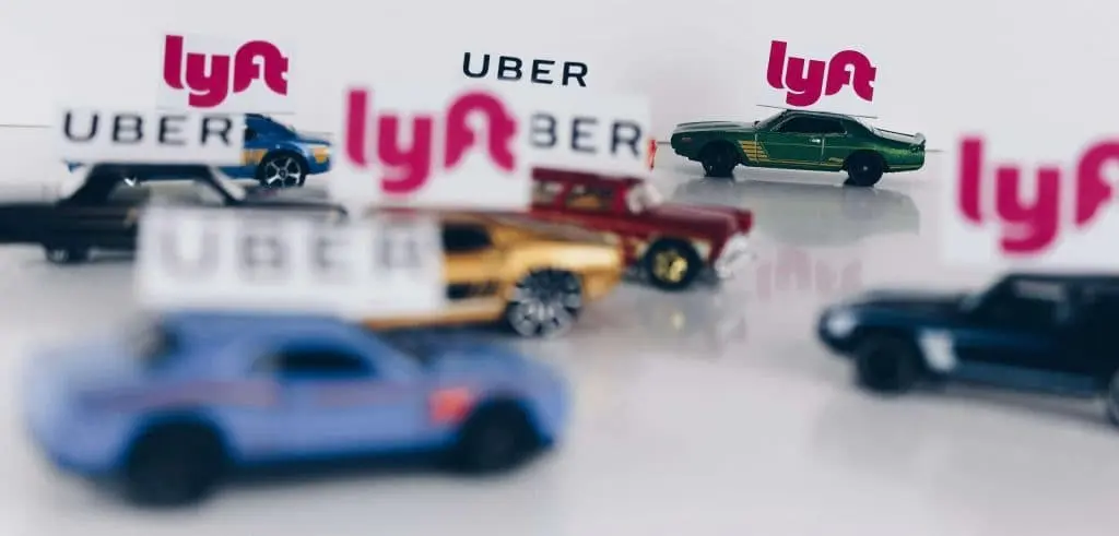 Uber and Lyft logos on top of toy cars