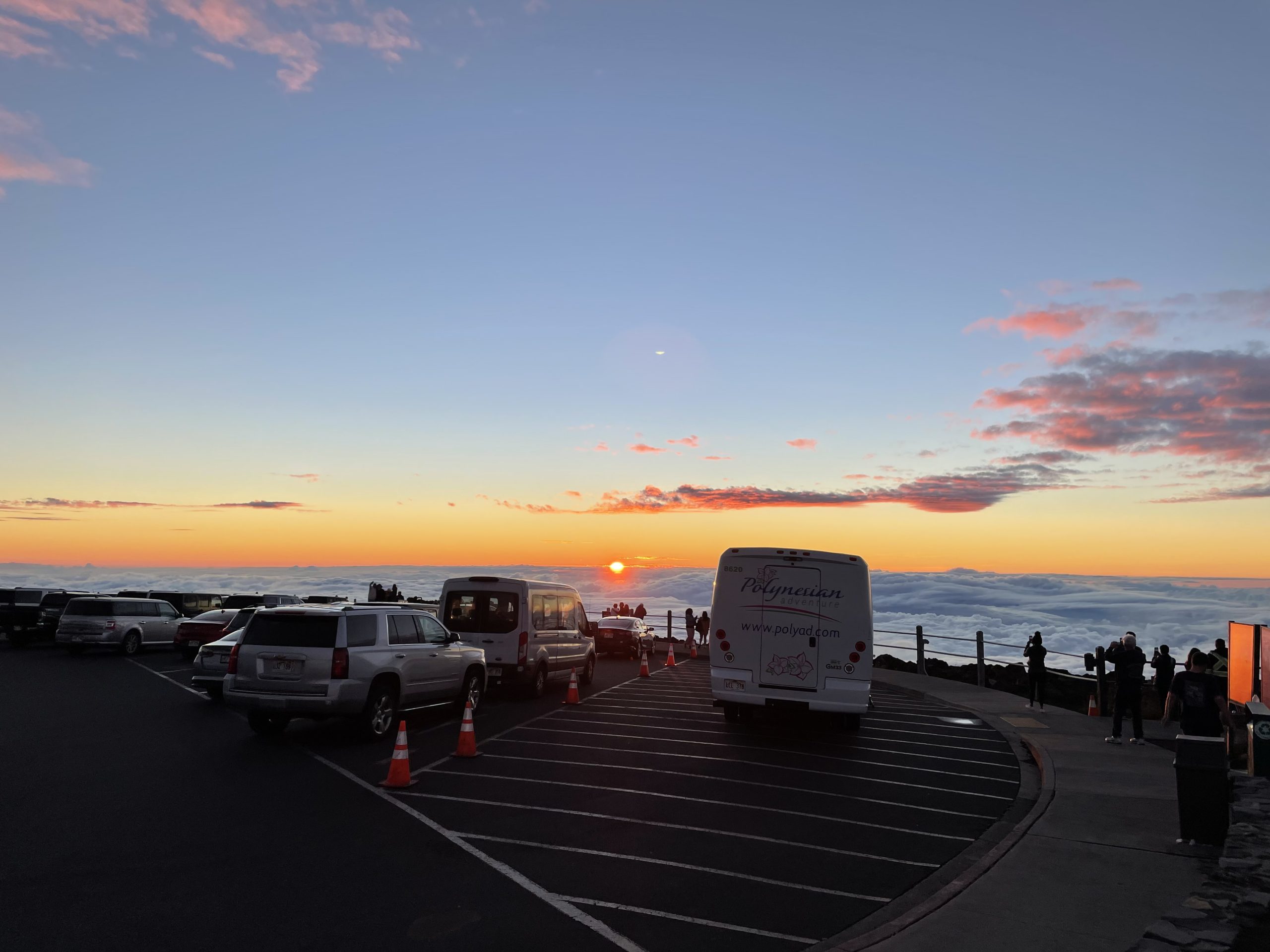 Visitors watching sunset above the clouds from the Haleakalā Visitor Center parking lot