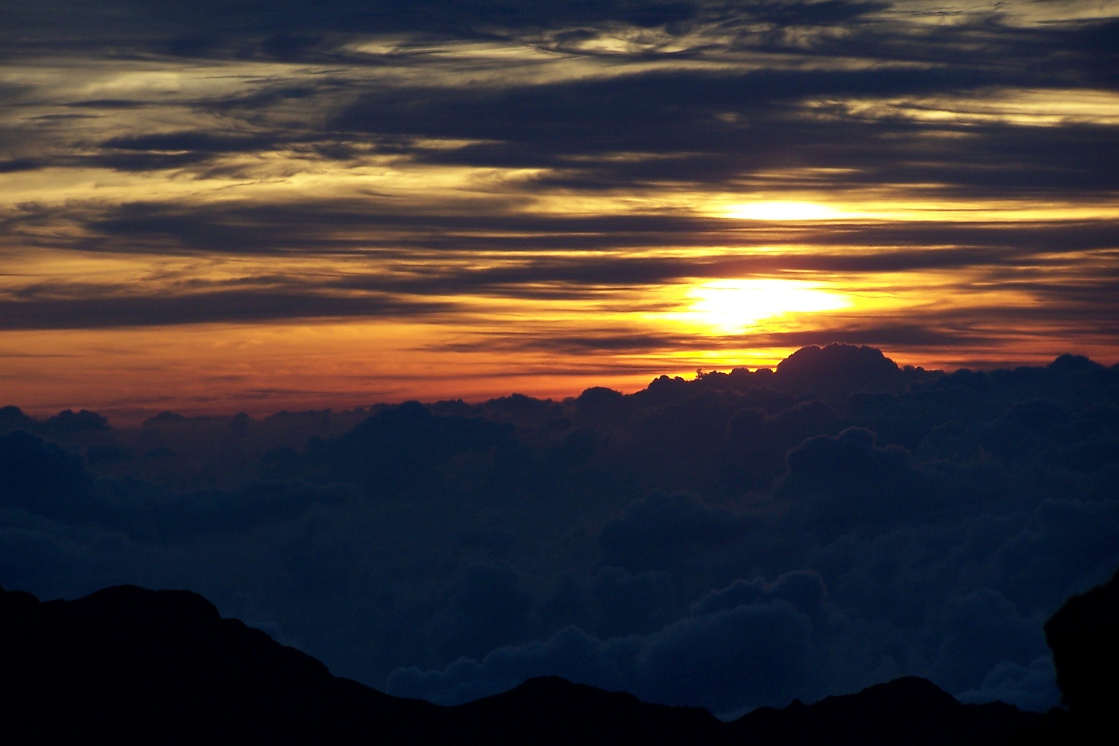 Orange dawn sky above clouds seen from Haleakalā’s summit